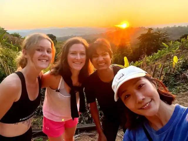 Guests smiling on a hilltop at sunset