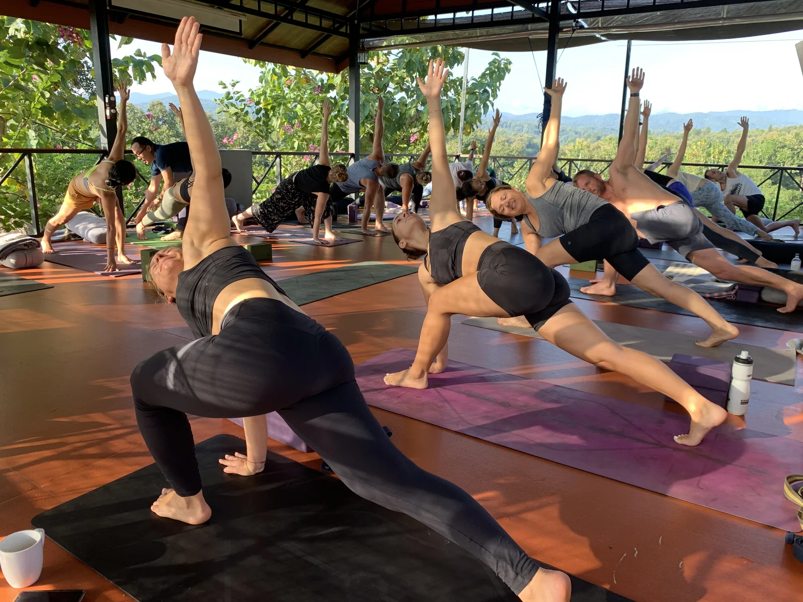 A morning yoga class stretching in low lunges with a view of the green hills