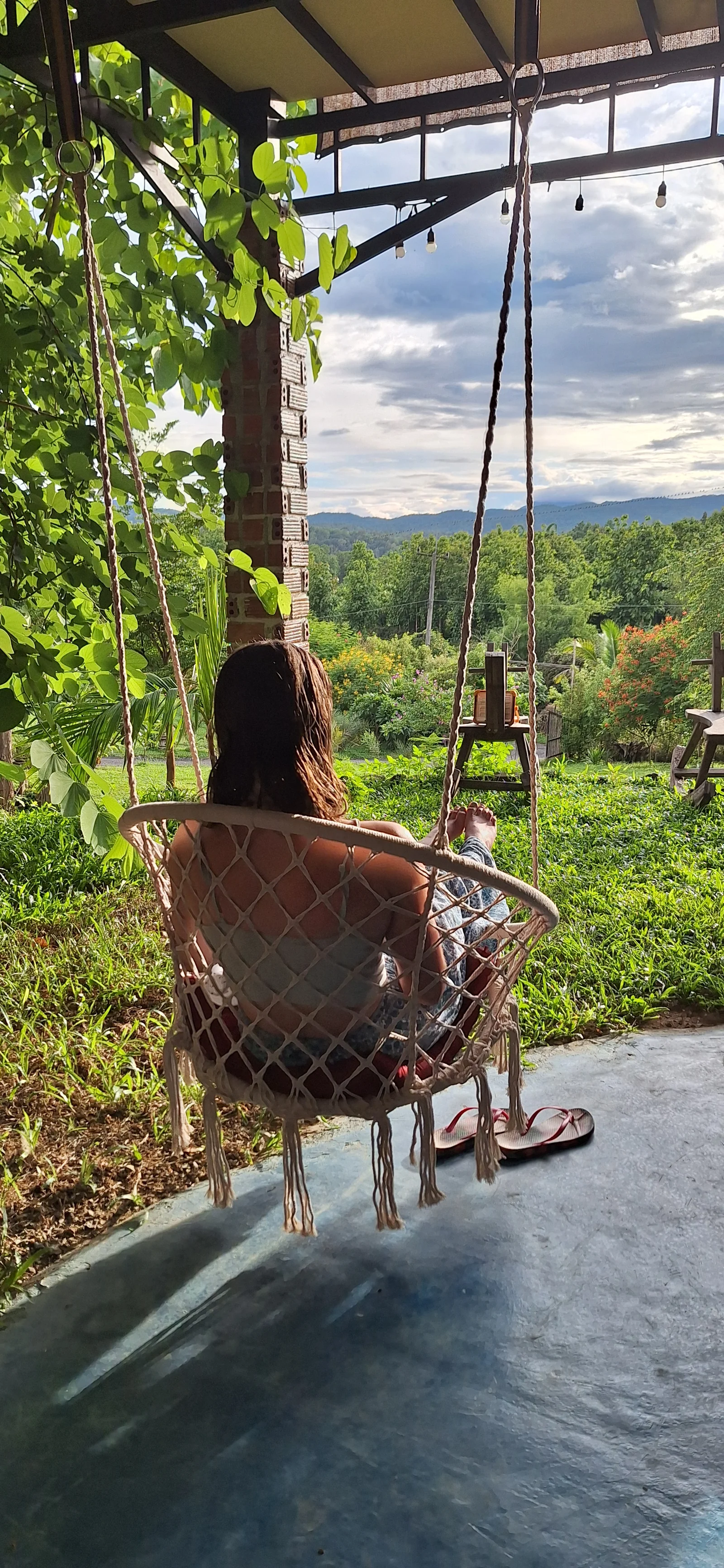A guest relaxing in a swing overlooking the gardens and green hills