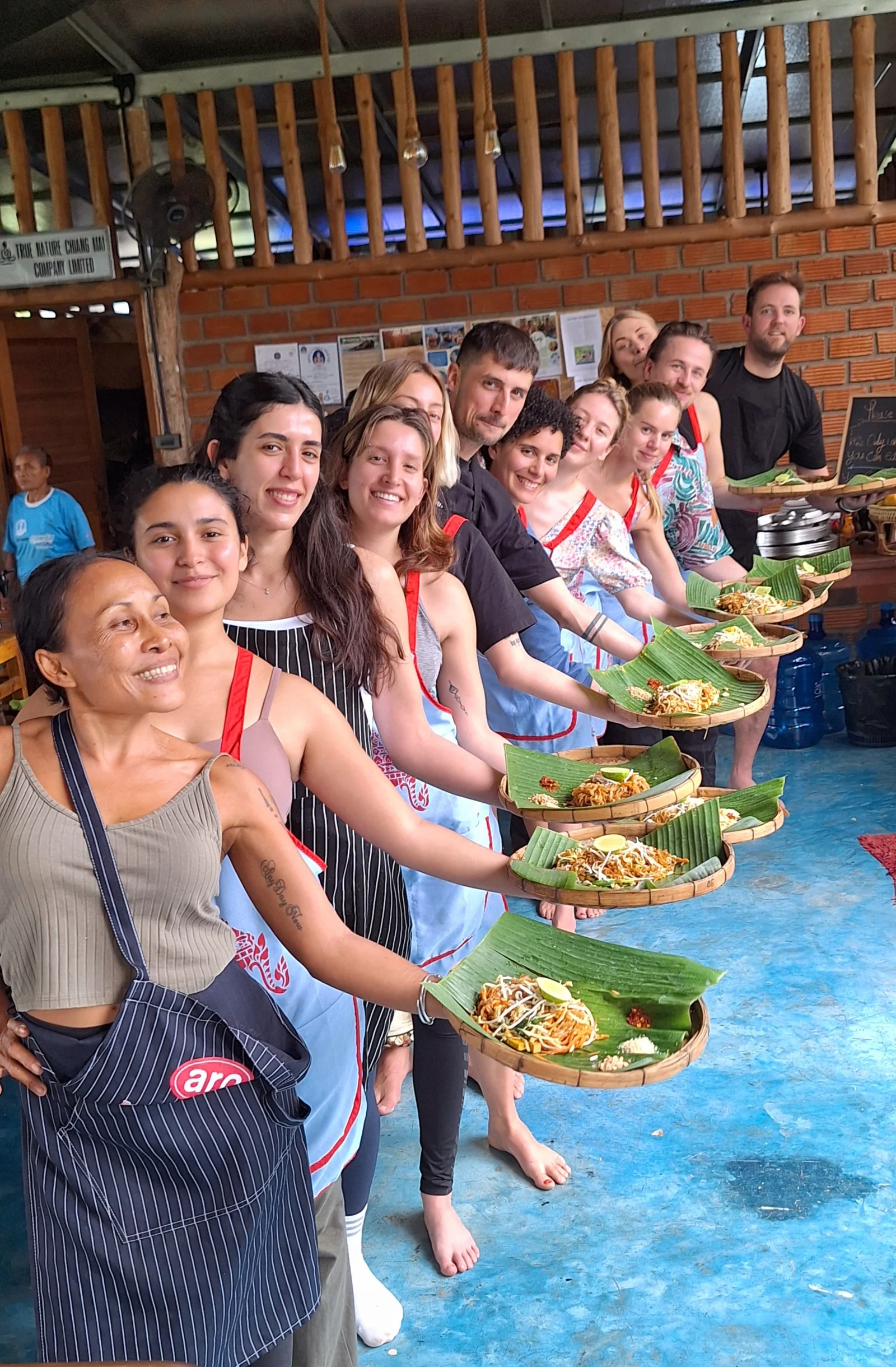 Guests proudly holding their finished dishes after a Thai cooking class