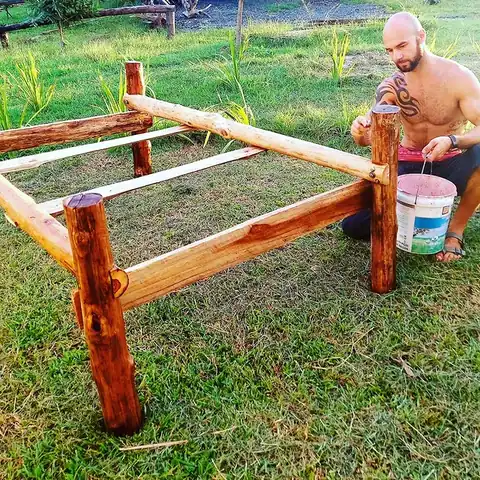 Adam hand-building a wooden bed frame in the garden