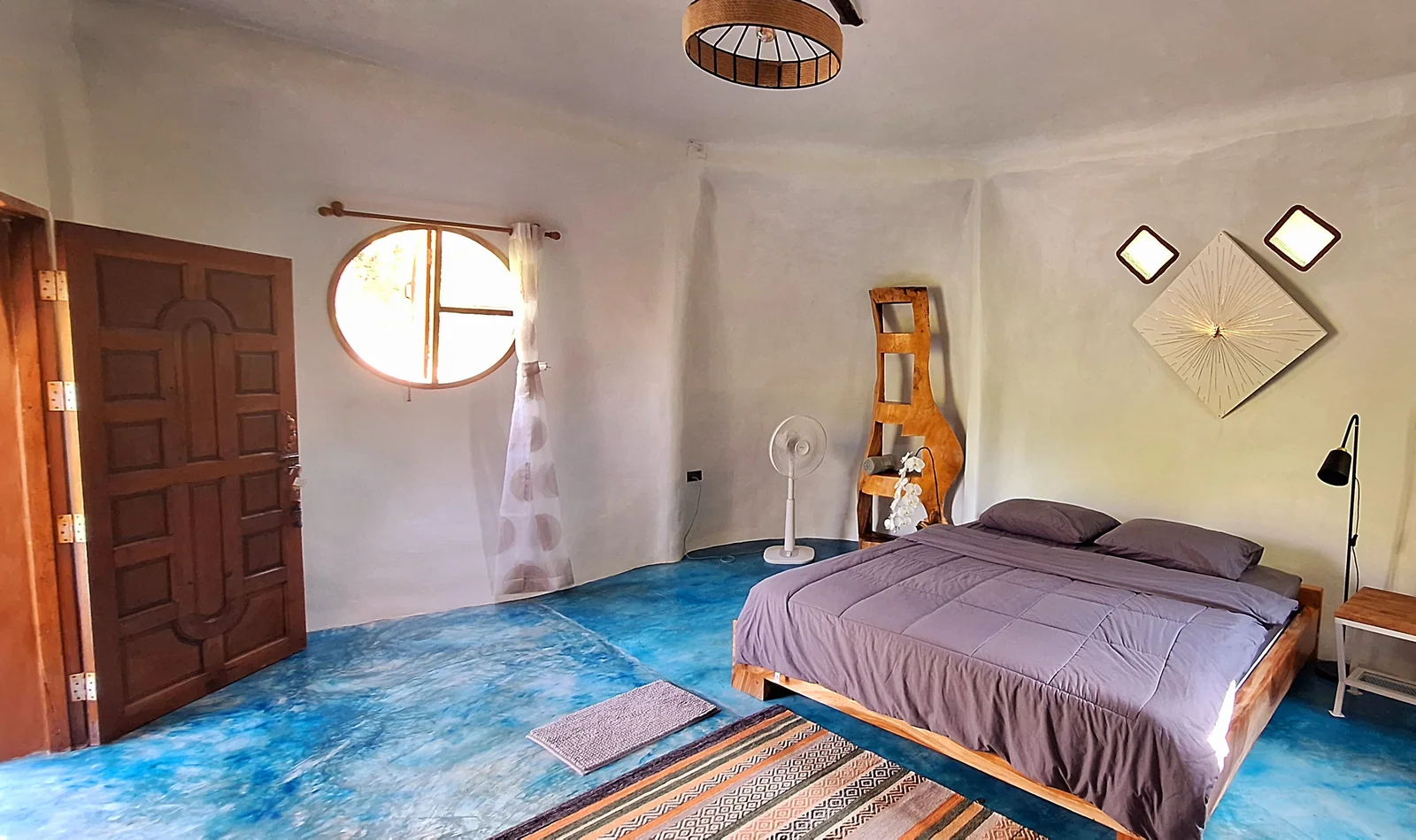 Mushroom House bedroom with a king-size bed, rounded walls and a circular window