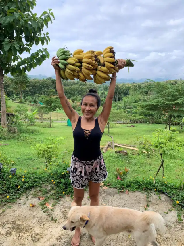 A guest holding up a huge bunch of bananas