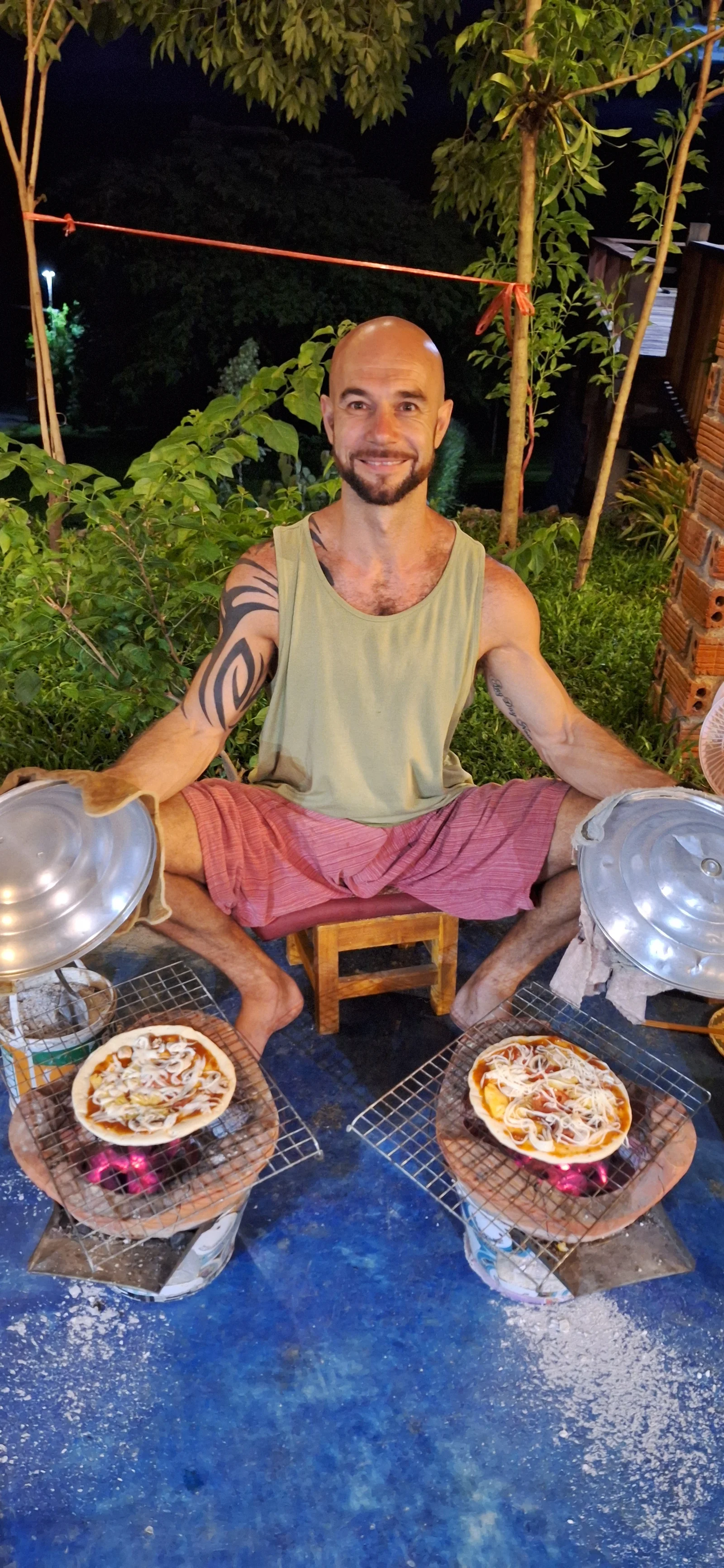 A guest cooking two pizzas over charcoal at Saturday pizza night