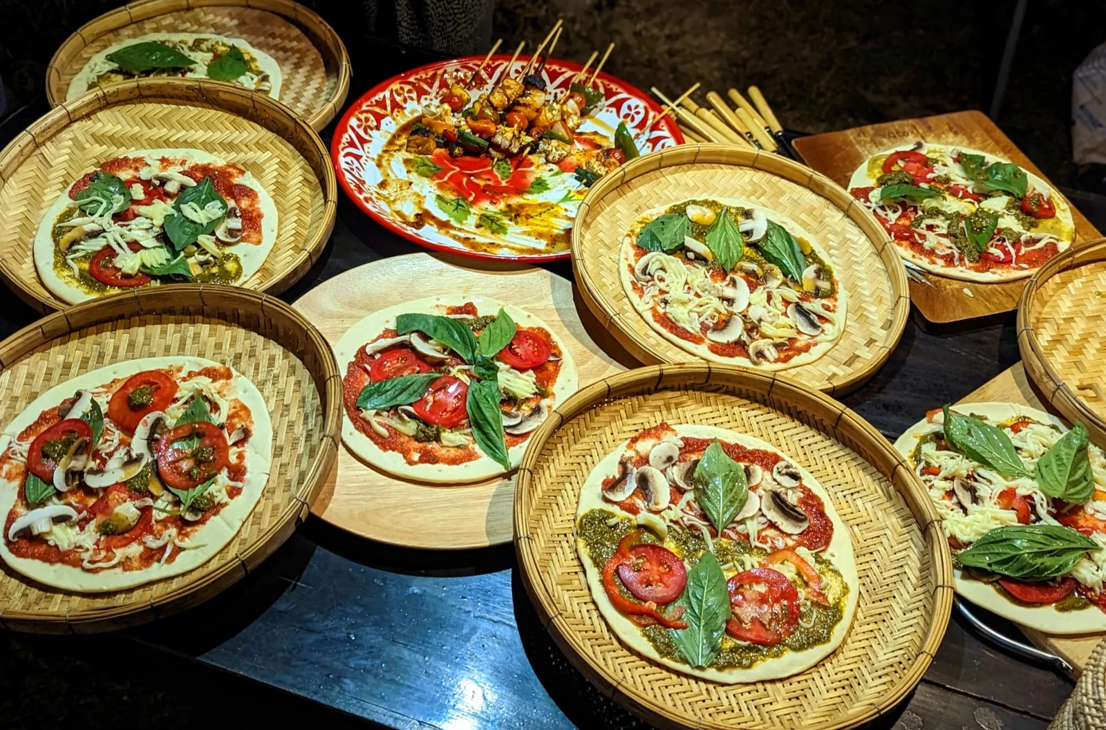Individual pizzas topped with vegetables, mushrooms and basil before cooking