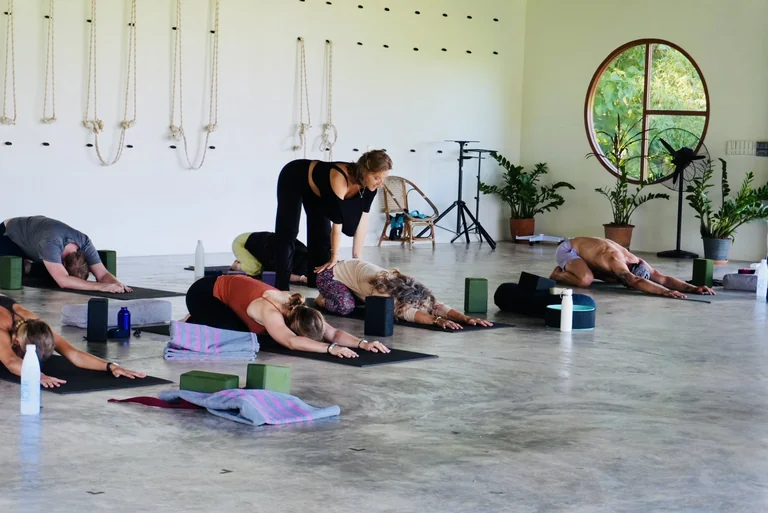 A teacher offering a gentle adjustment during yoga in the True Nature shala