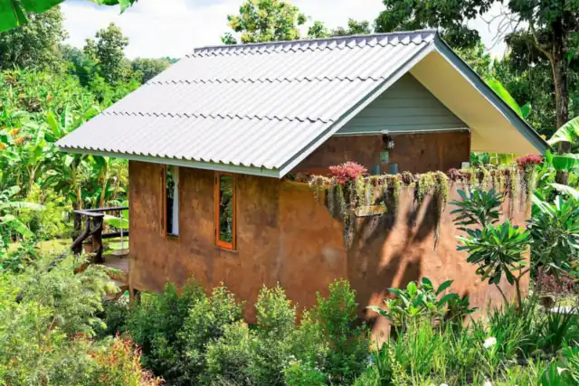 The Earth House, a small earth-walled house surrounded by flowers