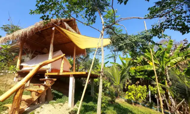 A nature tent on a raised teak platform with a sunshade