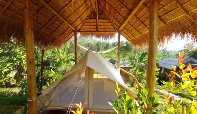 A canvas nature tent under a bamboo roof in the garden