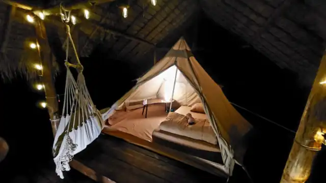 The nature tent lit up at night with a hammock