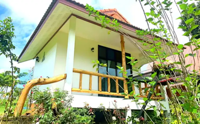 The Rose House, a white house with a wooden balcony among flowering plants
