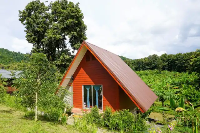 The Triangle House, a tall red A-frame house in the garden