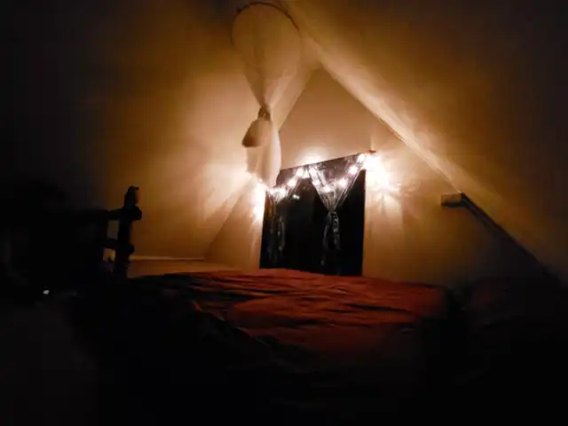 The loft bedroom of the Triangle House lit with fairy lights