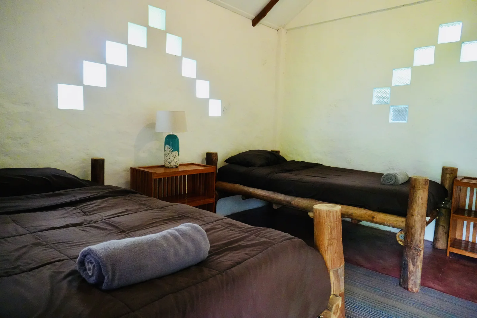 A simple twin room with handmade wooden beds and soft natural light