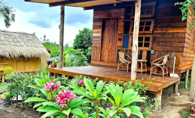 A wooden cottage with a deck and flowering garden