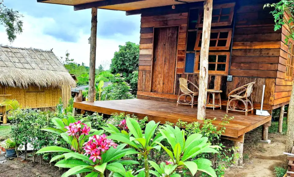 A wooden cottage with a deck and flowering garden