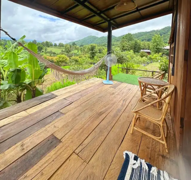 The wooden cottage balcony with a hammock and mountain view