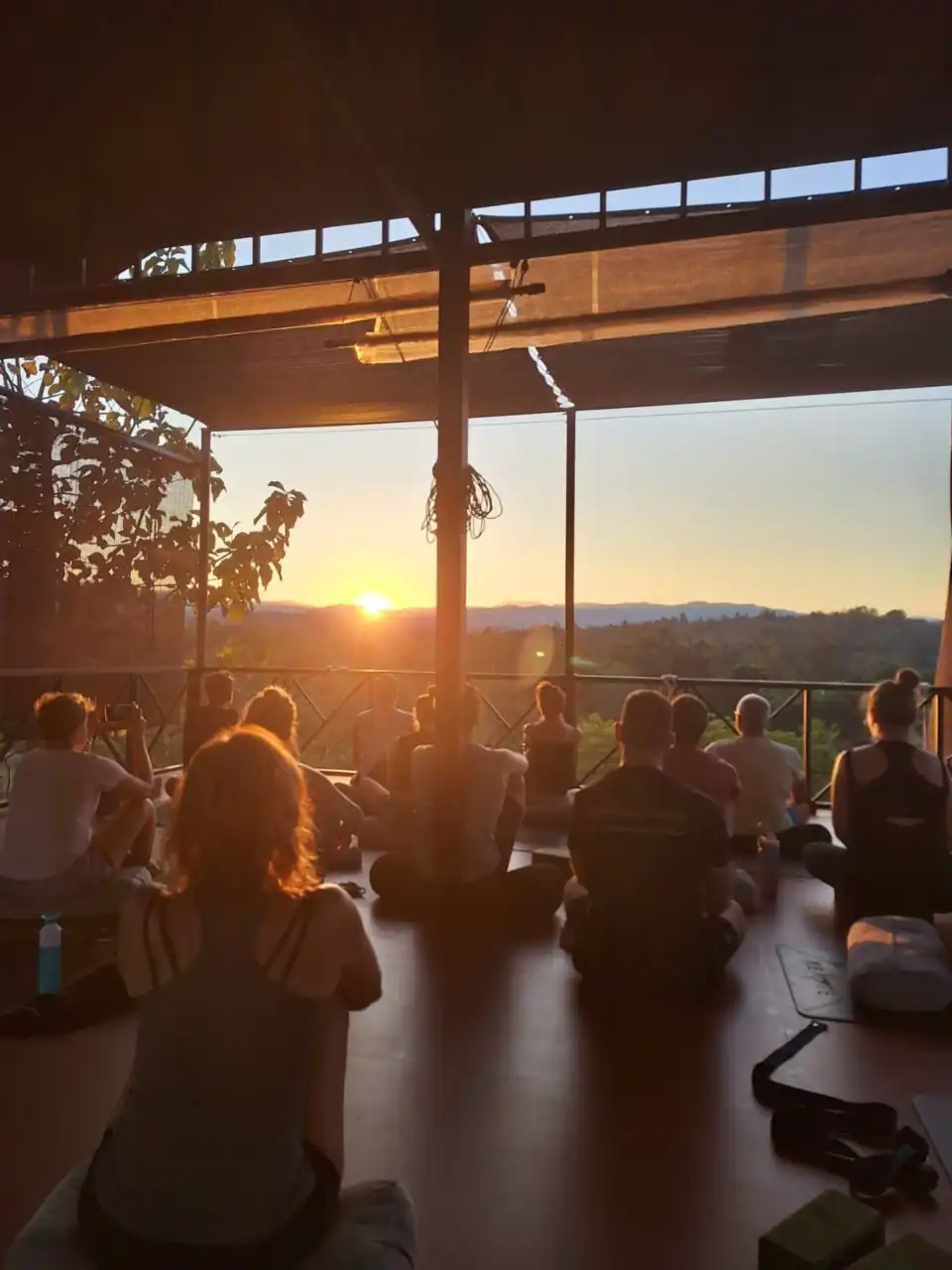 Guests sitting in the shala as the sun sets over the hills