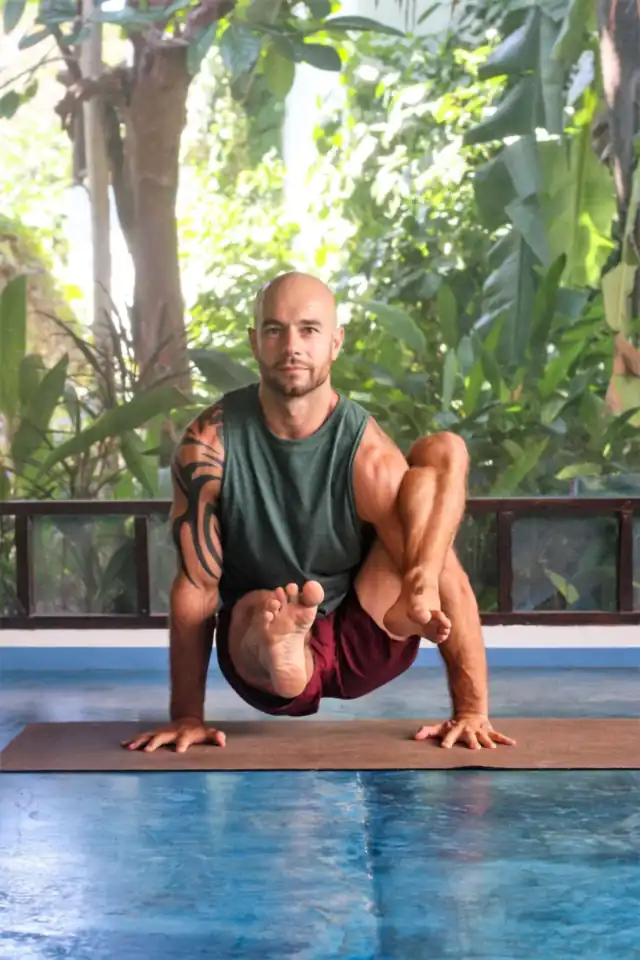 Adam in an arm balance on the shala deck