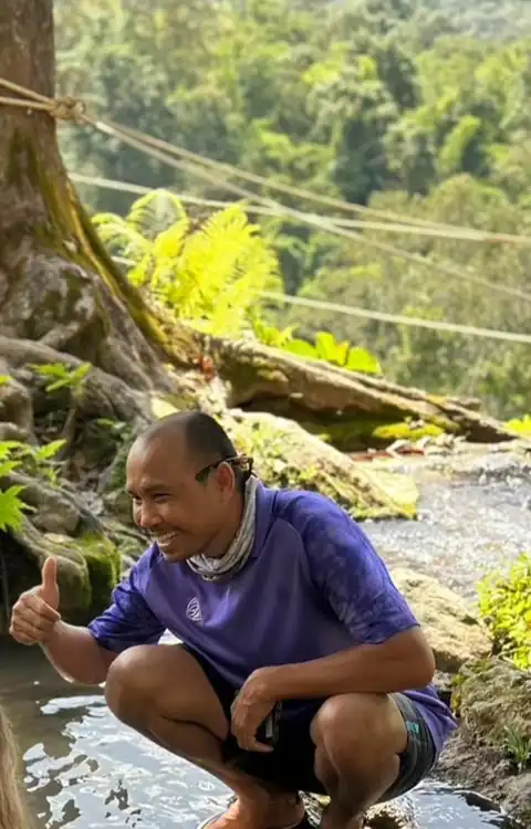 Oum crouching by a stream in the forest