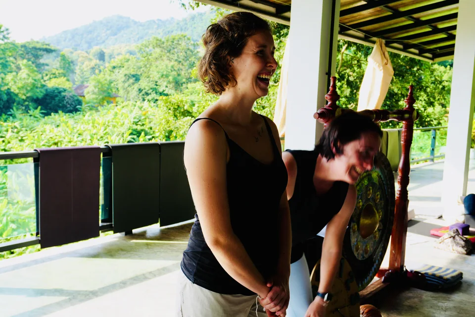 Two teacher training students sharing a smile beside the green hillside