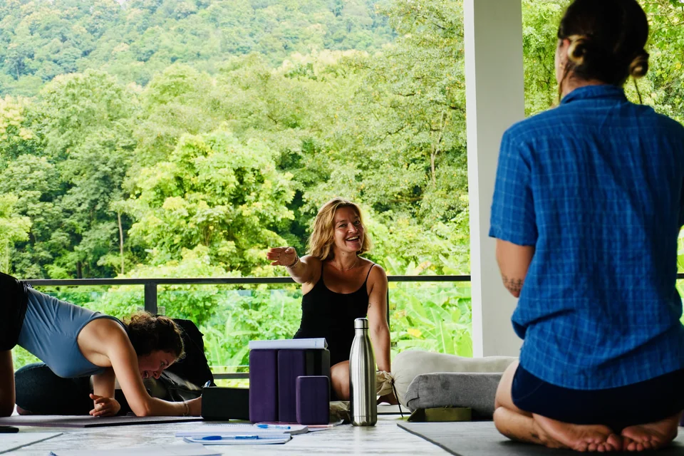 A teacher training student explaining a practice to classmates in the shala