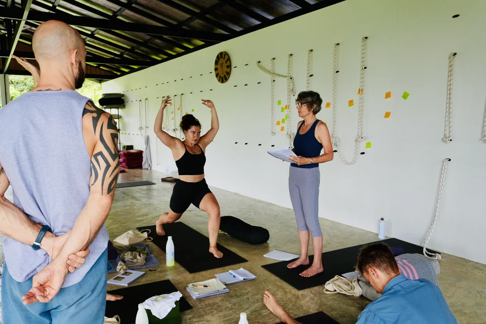 Students practising a standing posture while a classmate follows her teaching notes