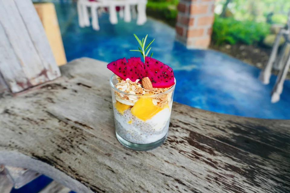 A colourful breakfast glass topped with fresh fruit and flowers