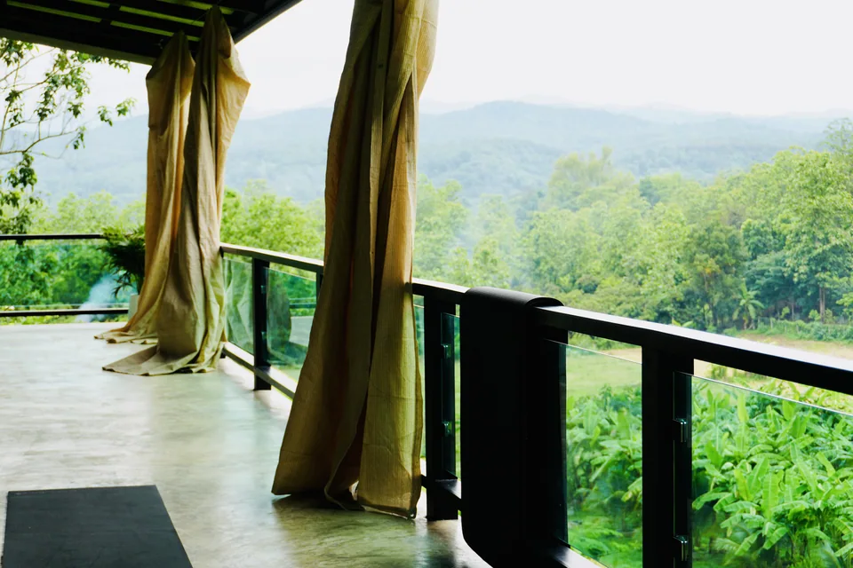 Green hills framed by the open windows and curtains of the shala