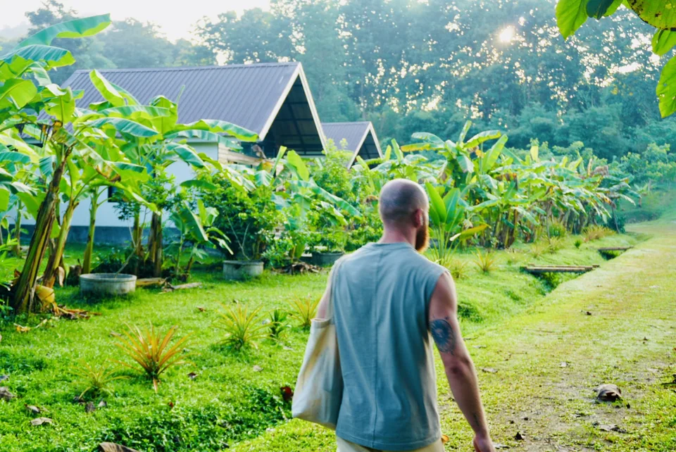 A guest walking beside the banana plants and hillside cottages