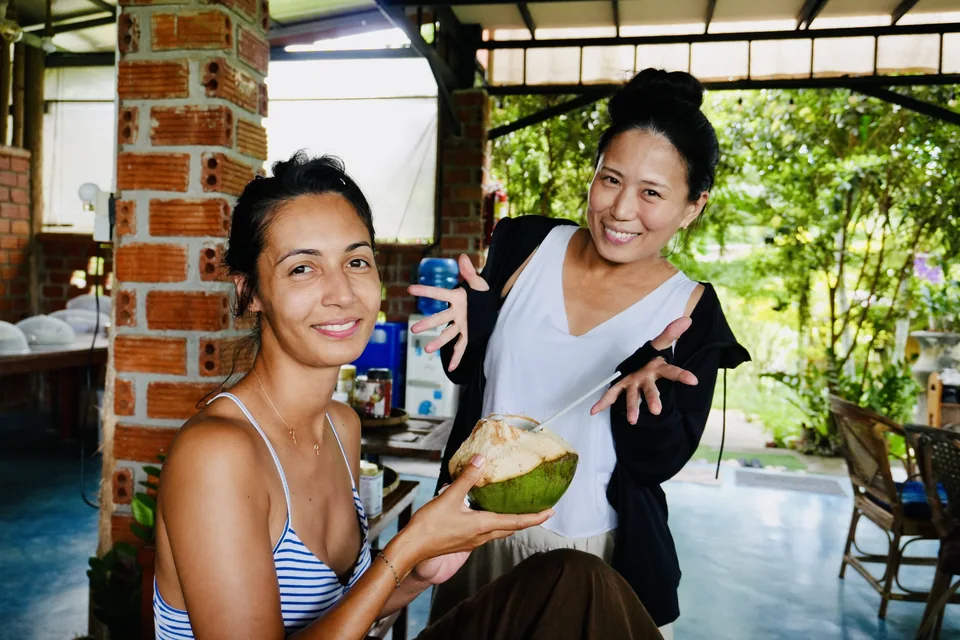 Two guests sharing fresh coconuts at the open-air dining table