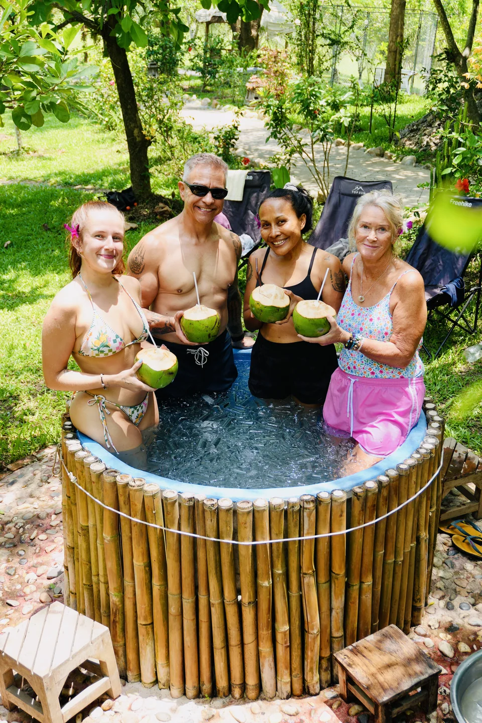Three guests smiling together beside the bamboo ice bath