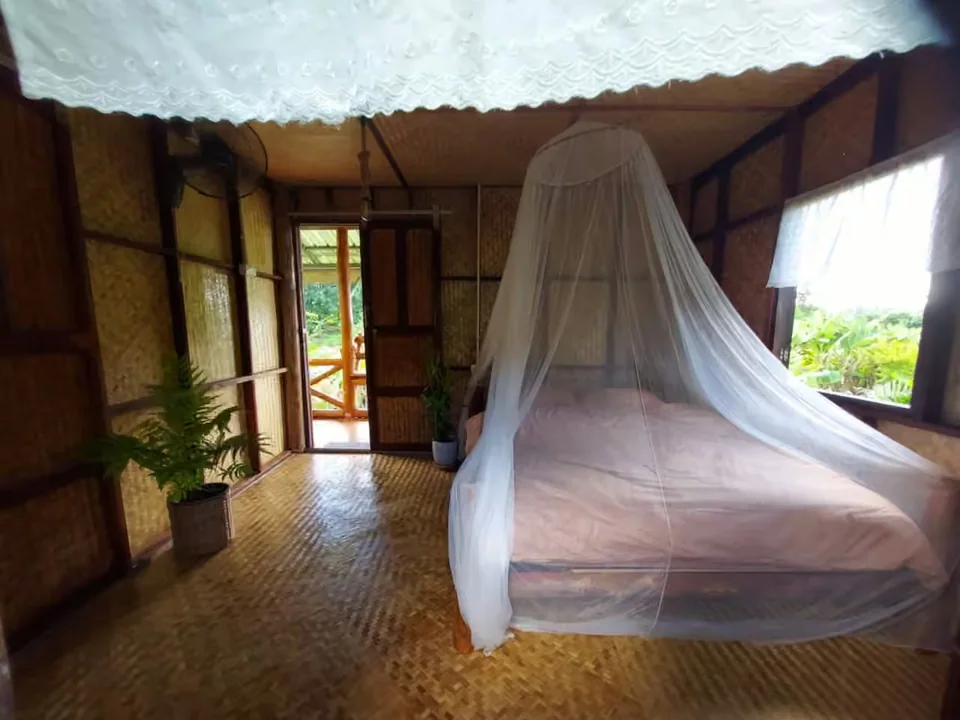 A simple private retreat room with a mosquito net and garden light