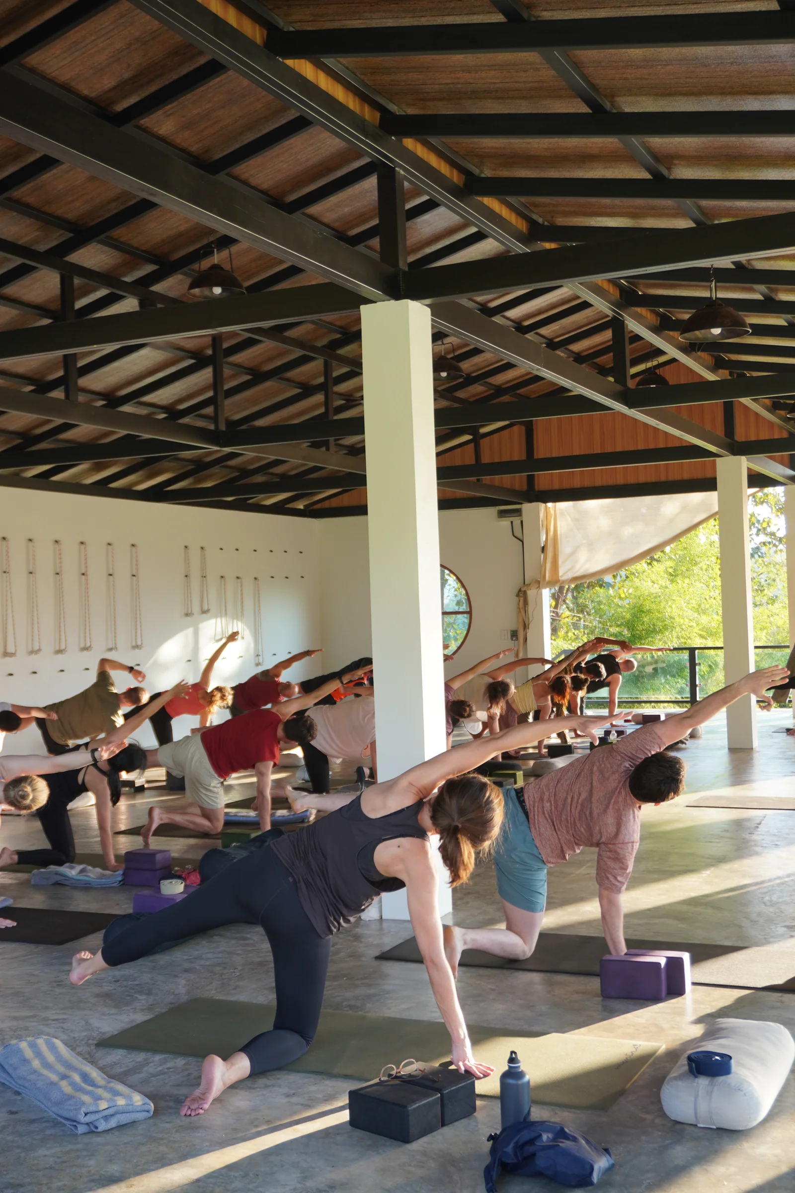 Guests taking a supported side stretch in the open-air shala