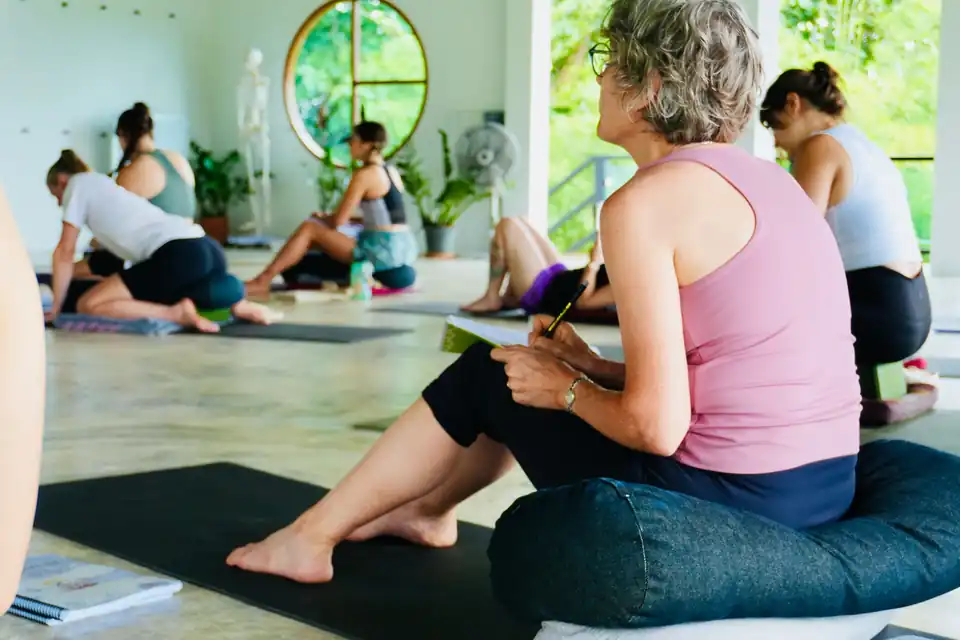 Teacher training students taking notes during a class in the shala
