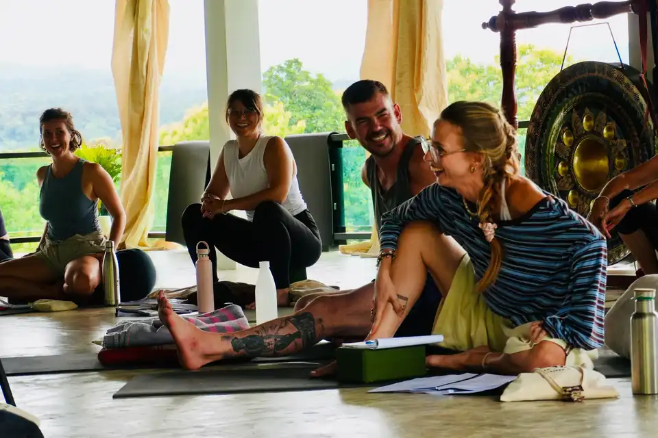 A student laughing with smiling classmates during teacher training in the True Nature shala